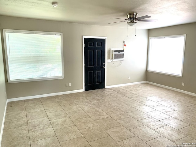 empty room with a wall mounted air conditioner, ceiling fan, and baseboards