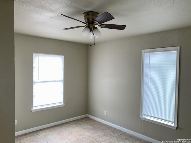 unfurnished room featuring a textured ceiling, ceiling fan, and baseboards