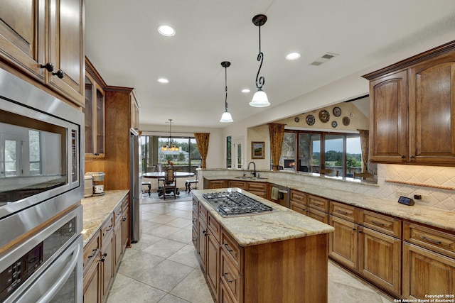 kitchen featuring a sink, visible vents, appliances with stainless steel finishes, backsplash, and light stone countertops