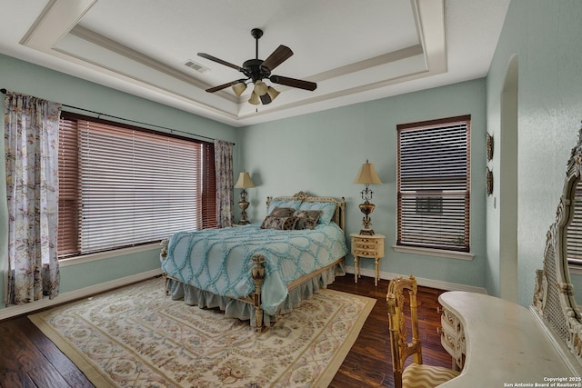 bedroom with a raised ceiling, visible vents, baseboards, and hardwood / wood-style flooring