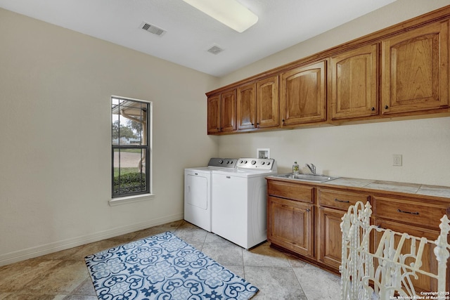 laundry area featuring cabinet space, visible vents, a sink, separate washer and dryer, and baseboards