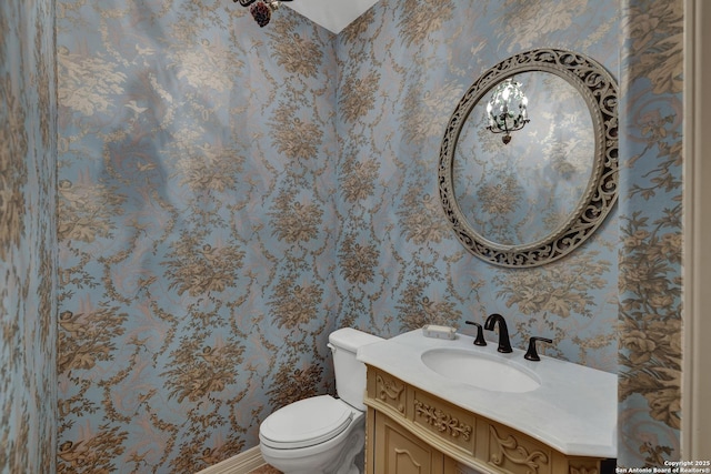 bathroom featuring vanity, toilet, and wallpapered walls