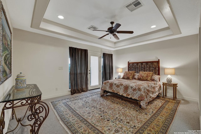 carpeted bedroom featuring a tray ceiling, visible vents, and baseboards