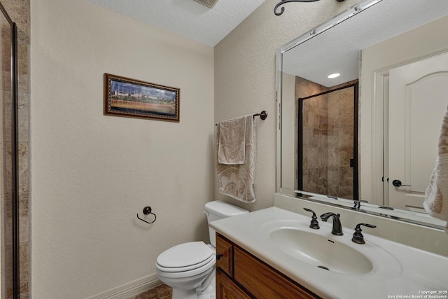 bathroom with baseboards, toilet, a textured ceiling, vanity, and a shower stall