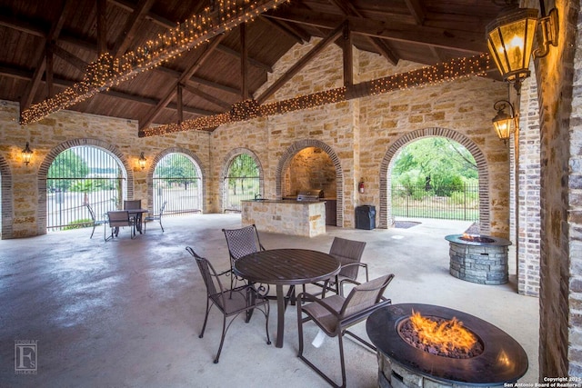 view of patio / terrace with outdoor dining area, fence, a fire pit, and an outdoor kitchen