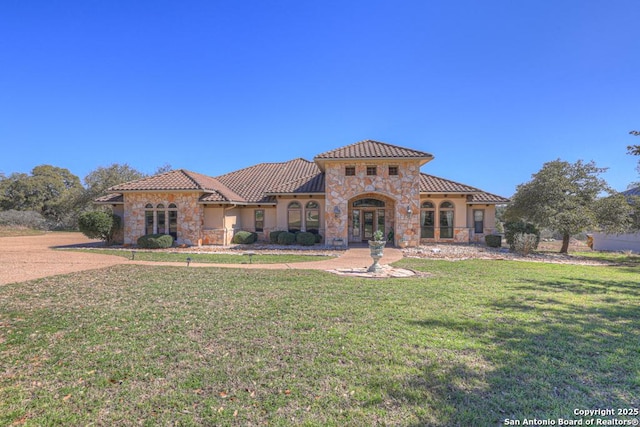 mediterranean / spanish-style home with french doors, stucco siding, a front yard, stone siding, and a tiled roof