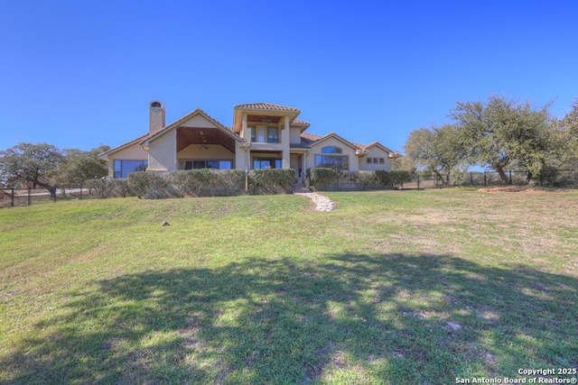 mediterranean / spanish-style home with fence, a chimney, and a front lawn