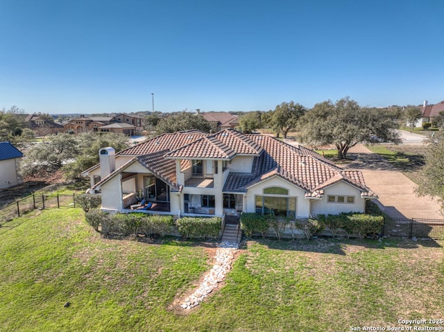 back of property featuring fence private yard, a tiled roof, stucco siding, and a yard