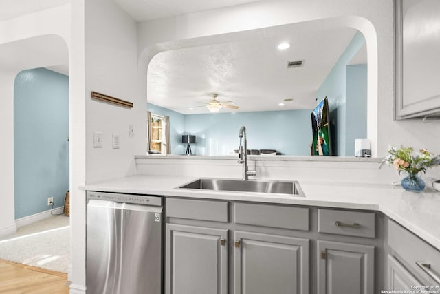 kitchen featuring dishwasher, light countertops, a sink, and gray cabinetry