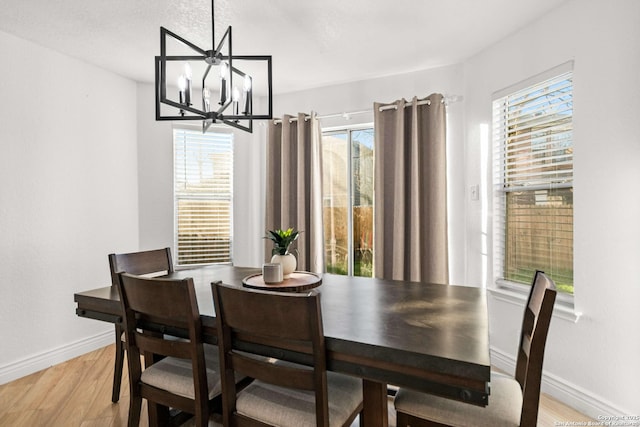 dining space featuring baseboards, a notable chandelier, and light wood-style floors