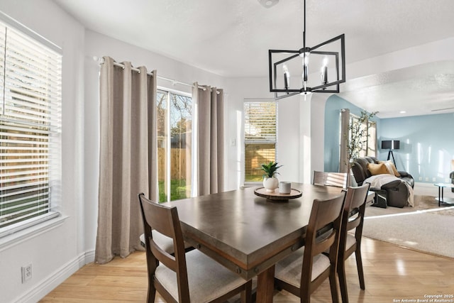 dining space featuring light wood-type flooring, an inviting chandelier, and baseboards