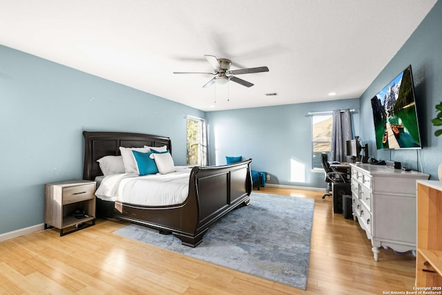 bedroom with light wood-style floors, visible vents, ceiling fan, and baseboards