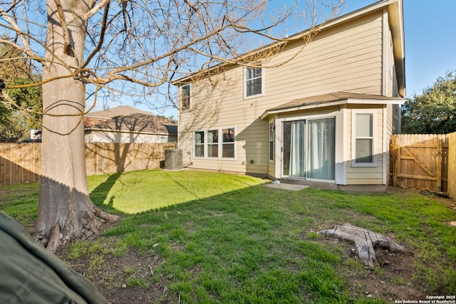 rear view of property featuring a lawn and a fenced backyard