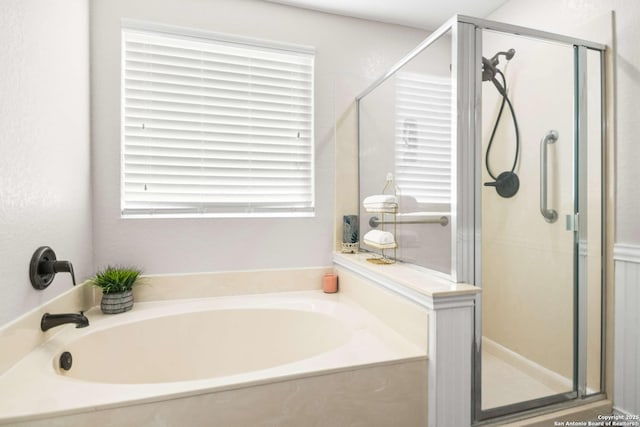 bathroom featuring a stall shower and a bath