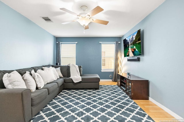 living area featuring baseboards, visible vents, a ceiling fan, and wood finished floors