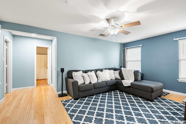 living room with ceiling fan, wood finished floors, visible vents, and baseboards