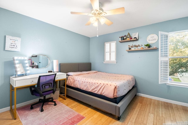 bedroom featuring a ceiling fan, light wood-style flooring, and baseboards