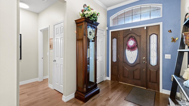 entryway featuring baseboards, light wood finished floors, and crown molding