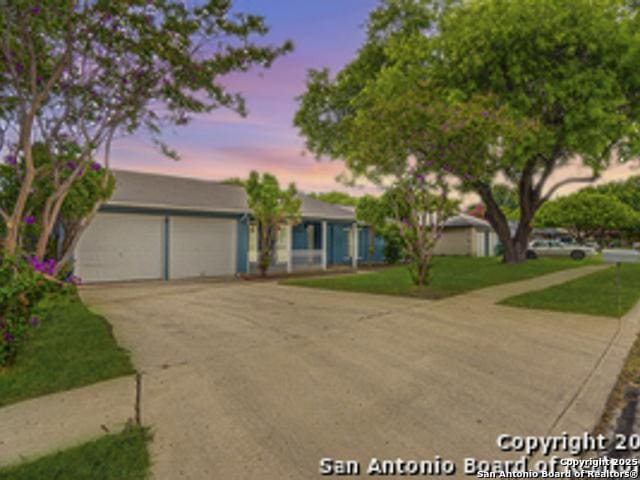 view of front of house with a garage, concrete driveway, and a yard