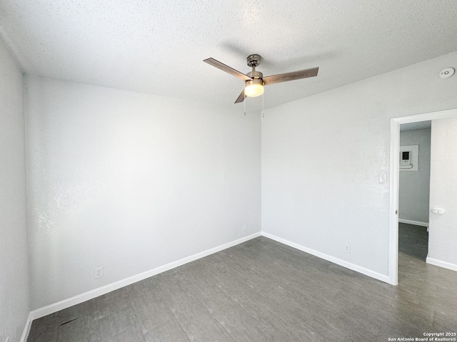 unfurnished room featuring ceiling fan, a textured ceiling, baseboards, and dark wood-style flooring