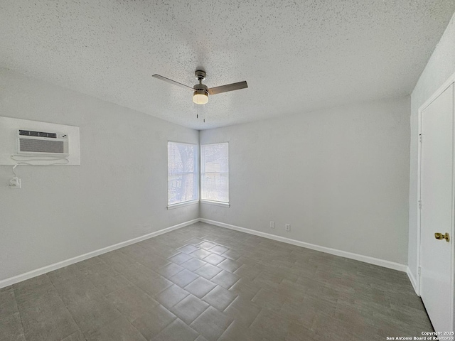 spare room featuring a ceiling fan, baseboards, a textured ceiling, and an AC wall unit