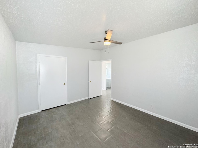 unfurnished bedroom featuring a textured ceiling, ceiling fan, dark wood-type flooring, and baseboards