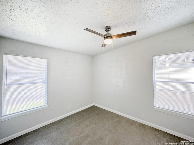 spare room with plenty of natural light, a textured ceiling, baseboards, and ceiling fan