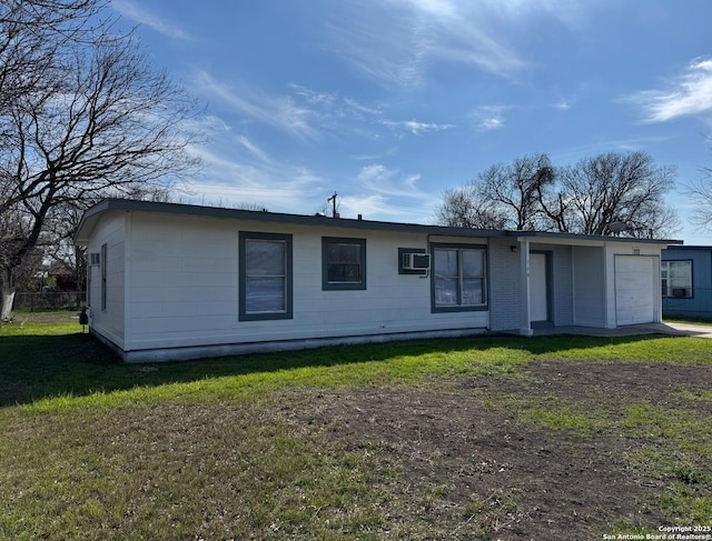 rear view of property featuring an attached garage, a yard, and a wall mounted AC