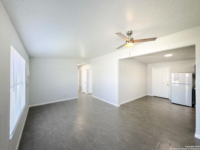 unfurnished room with dark wood-style floors, a textured ceiling, baseboards, and a ceiling fan