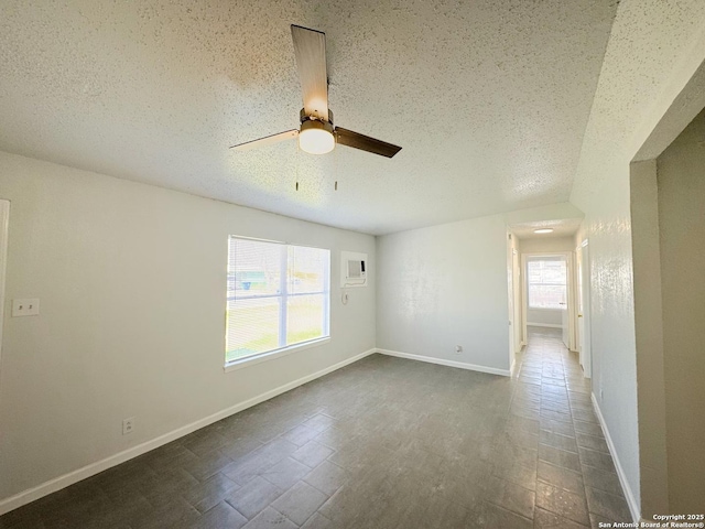 empty room featuring a ceiling fan, a textured ceiling, and baseboards