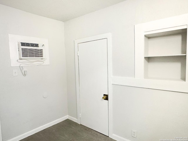 interior space featuring a wall unit AC and baseboards