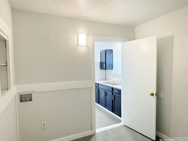 bathroom with a textured ceiling, vanity, and baseboards