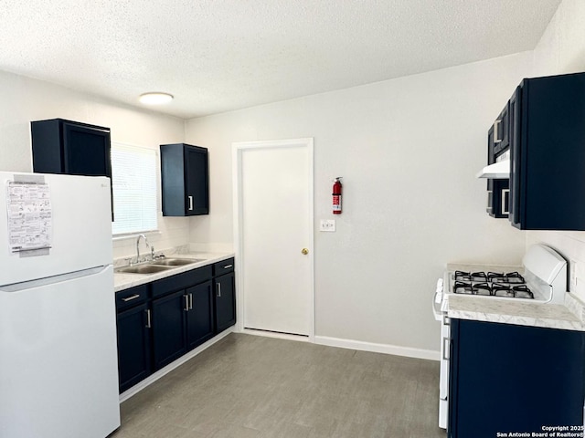 kitchen featuring white appliances, baseboards, light countertops, and a sink