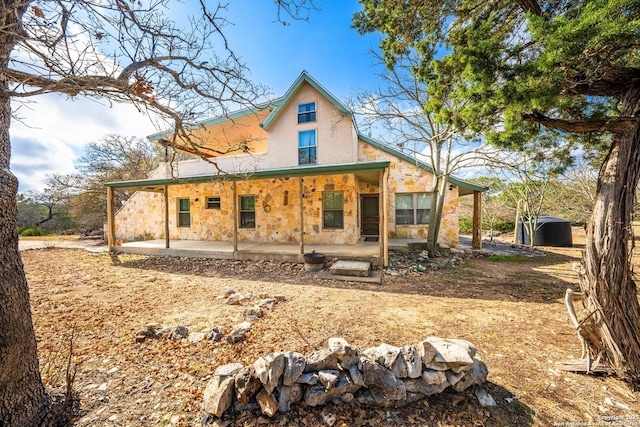 rear view of house with stone siding, a patio area, and stucco siding