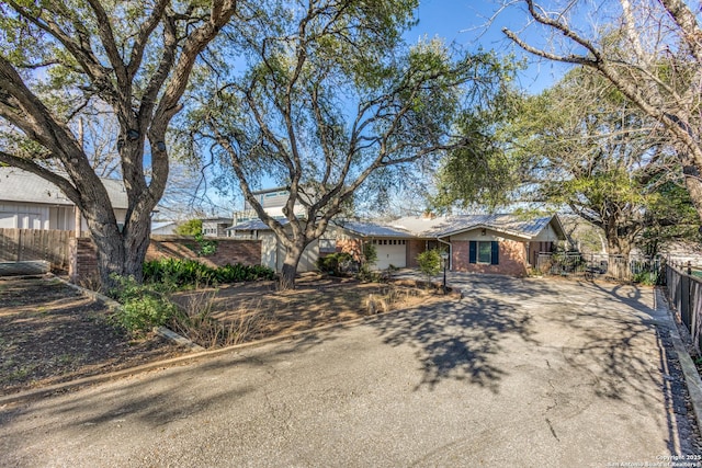 ranch-style home featuring driveway, a garage, fence, and brick siding