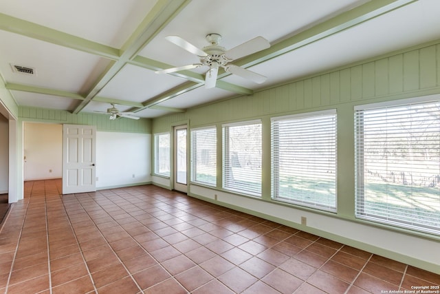 tiled empty room featuring baseboards, coffered ceiling, a wealth of natural light, and beamed ceiling