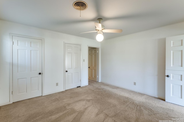 unfurnished bedroom featuring baseboards, visible vents, a ceiling fan, and light colored carpet