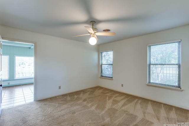 empty room featuring light carpet, ceiling fan, and visible vents