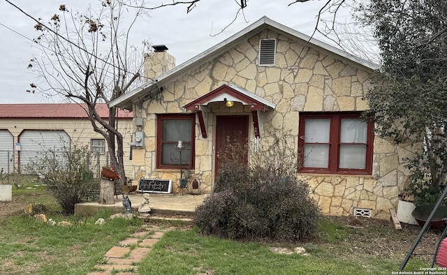 view of front of property featuring stone siding and a chimney