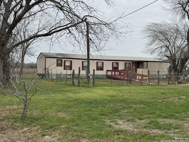 rear view of property featuring a yard and fence