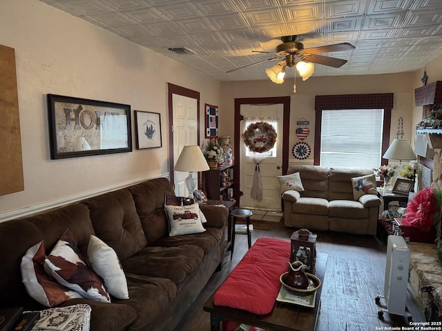 living room featuring visible vents, ceiling fan, wood finished floors, and an ornate ceiling