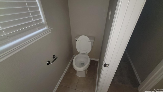 bathroom with baseboards, toilet, and tile patterned floors