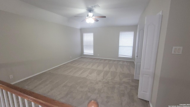 unfurnished room featuring visible vents, a ceiling fan, light colored carpet, and baseboards