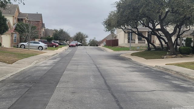 view of road with a residential view, curbs, sidewalks, and street lights