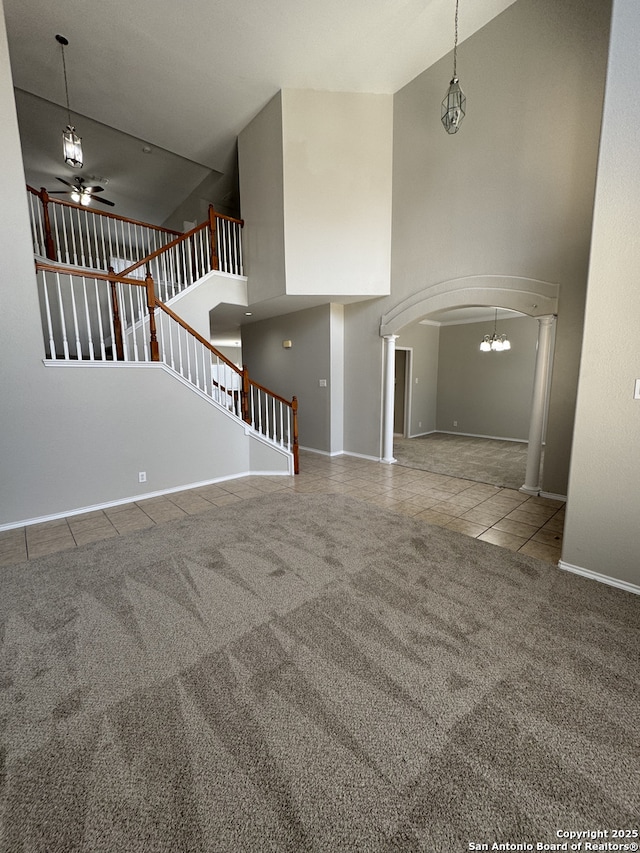 unfurnished living room with arched walkways, stairway, carpet, and tile patterned flooring