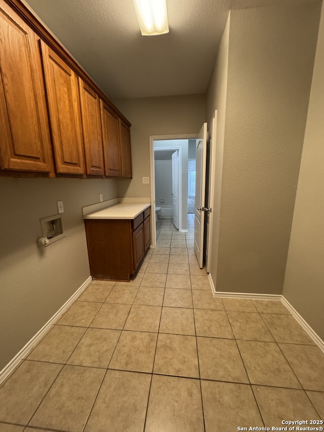 laundry area featuring cabinet space, baseboards, light tile patterned floors, and washer hookup