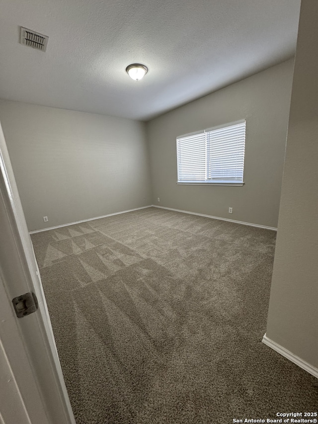 unfurnished room featuring baseboards, carpet, visible vents, and a textured ceiling