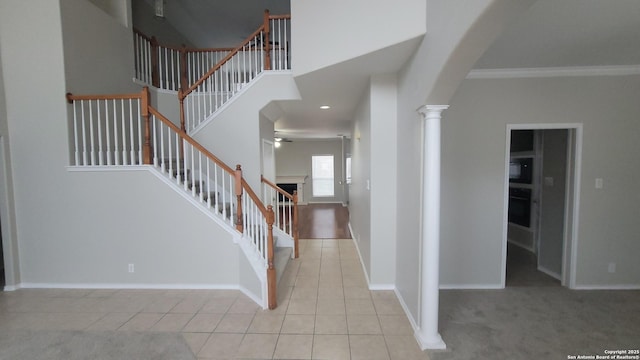 foyer entrance with arched walkways, light tile patterned floors, a towering ceiling, baseboards, and decorative columns