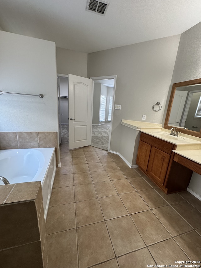 bathroom featuring tile patterned flooring, a garden tub, vanity, visible vents, and baseboards