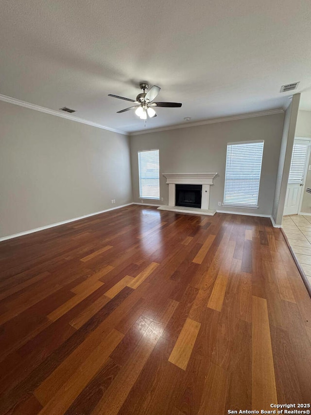 unfurnished living room with crown molding, a fireplace, a ceiling fan, and wood finished floors